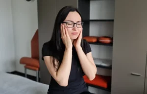 Physiotherapeutin Irina Rakovic demonstriert Kieferschmerzen (Symptome von CMD) in ihrer Privatpraxis Deifilia in Frankfurt-Sachsenhausen.