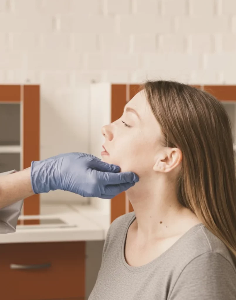 Therapeutin mit Handschuh untersucht Kiefergelenk einer Patientin bei einer CMD-Behandlung.